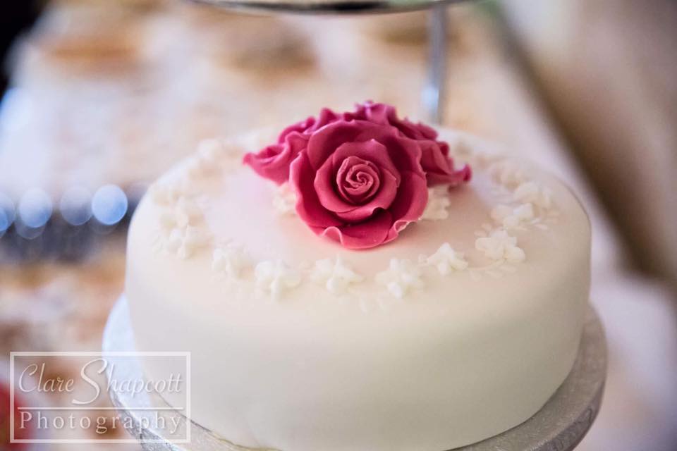Beautiful pink flower on top of dainty white wedding cake