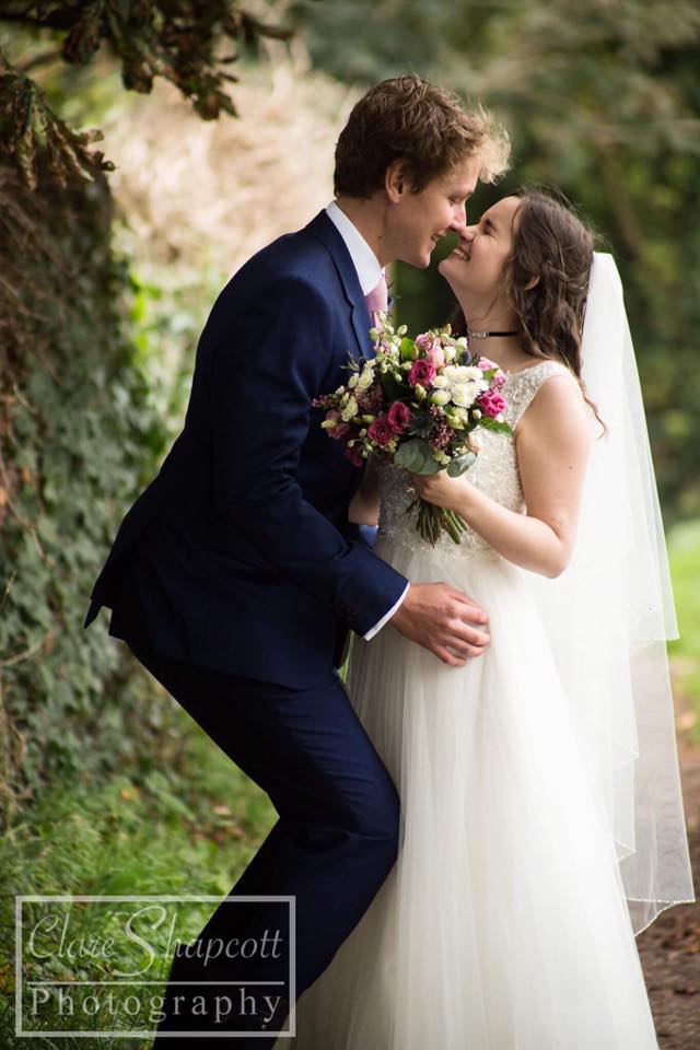 Professional photograph of groom bending down to kiss bride holding flowers