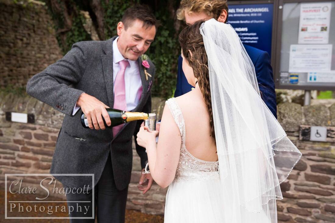 Man pours champagne for bride outside church