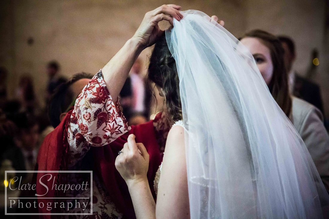 guest adjust white veil on brides head after wedding
