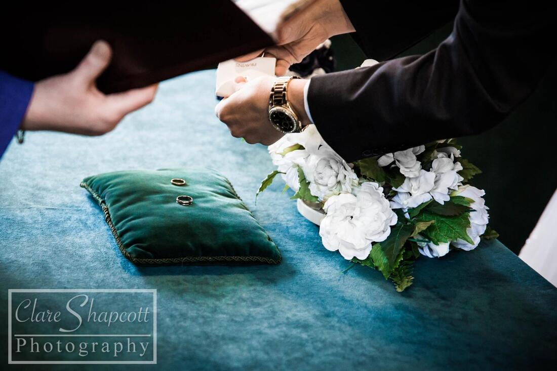 Wedding rings on cushion next to white flowers