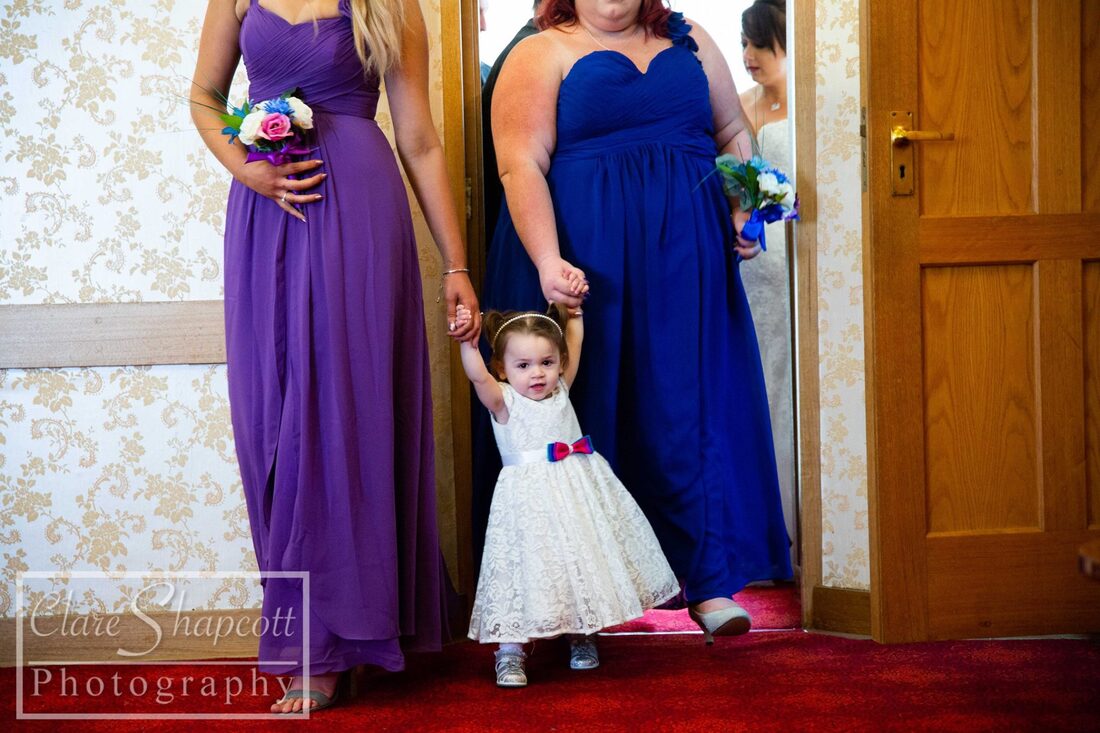 Bridesmaids holding hands of flower girl at wedding ceremony in dresses