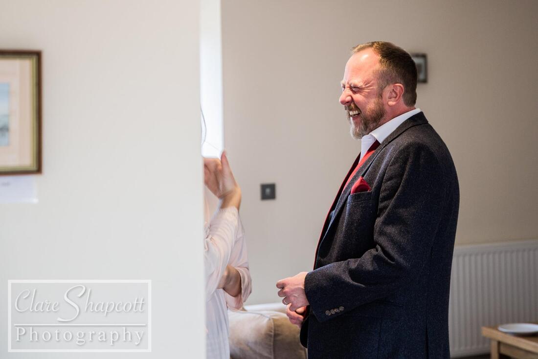 Father of bride laughs while in white room