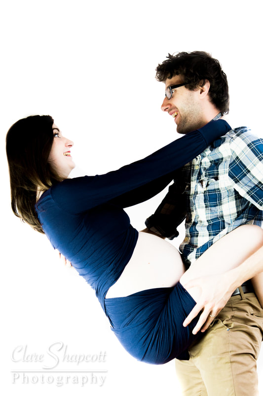 Photograph of husband carrying pregnant wife while smiling