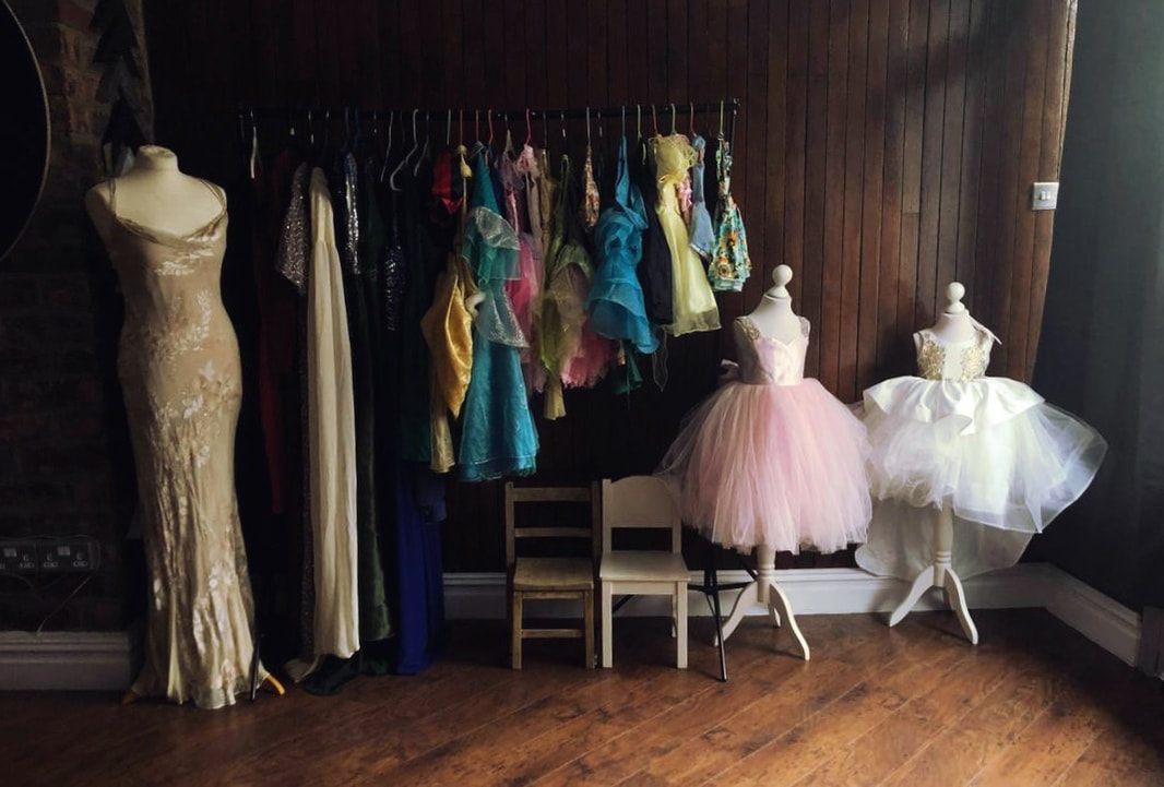 Various dresses on display, some adult and some children's dresses on either a hanging line or on mannequins.