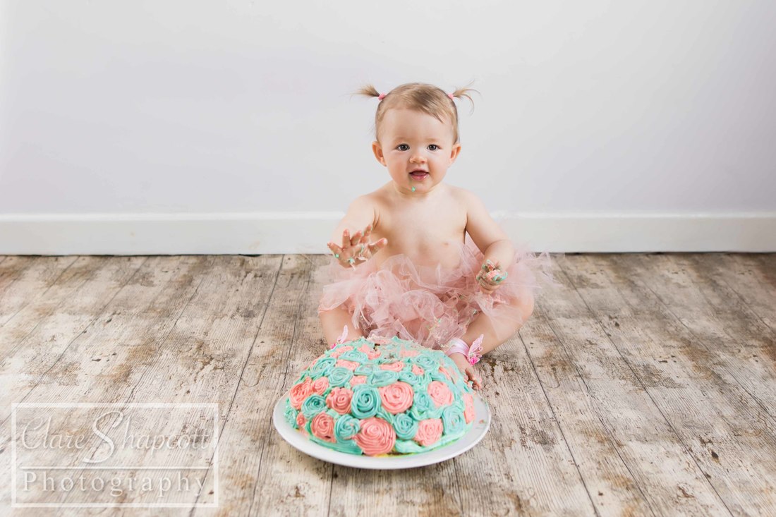 Baby girl in a pink tutu enjoying a cake smash at our studio in Henbury.