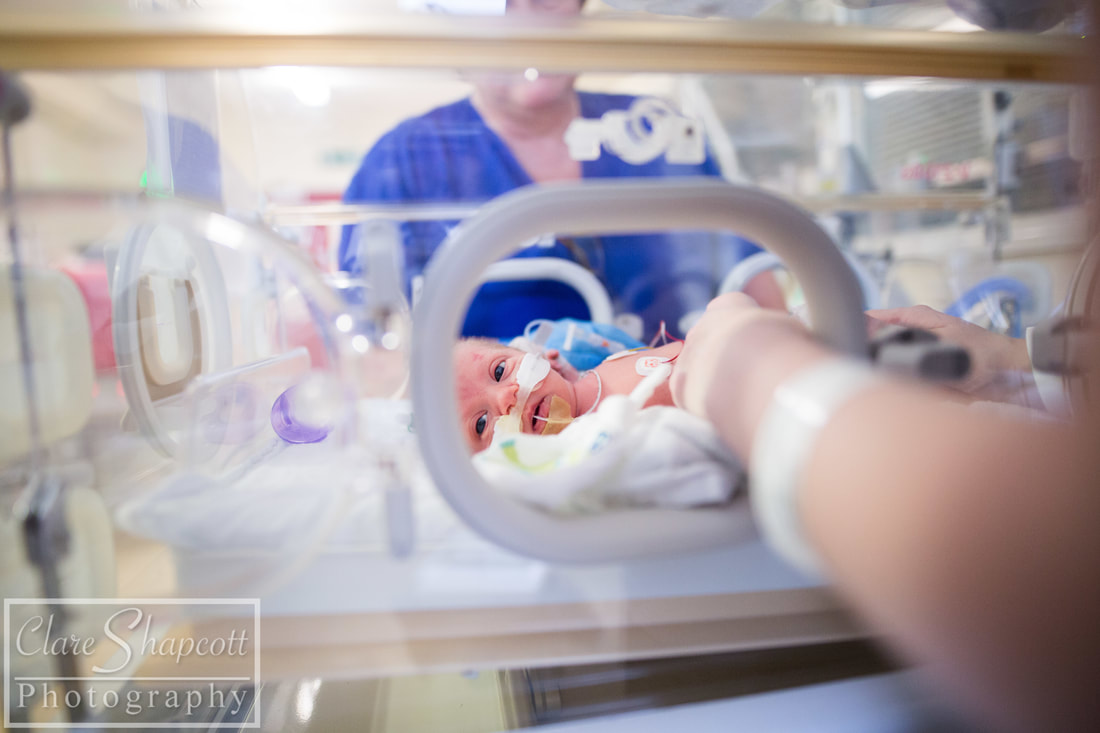 Picture of premature baby at nicu in an incubator with feeding tube and nurse