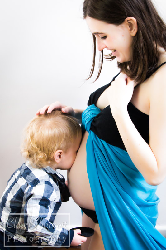 Brother kissing mother's tummy while pregnant