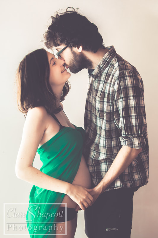 Green material kissing husband during maternity shoot