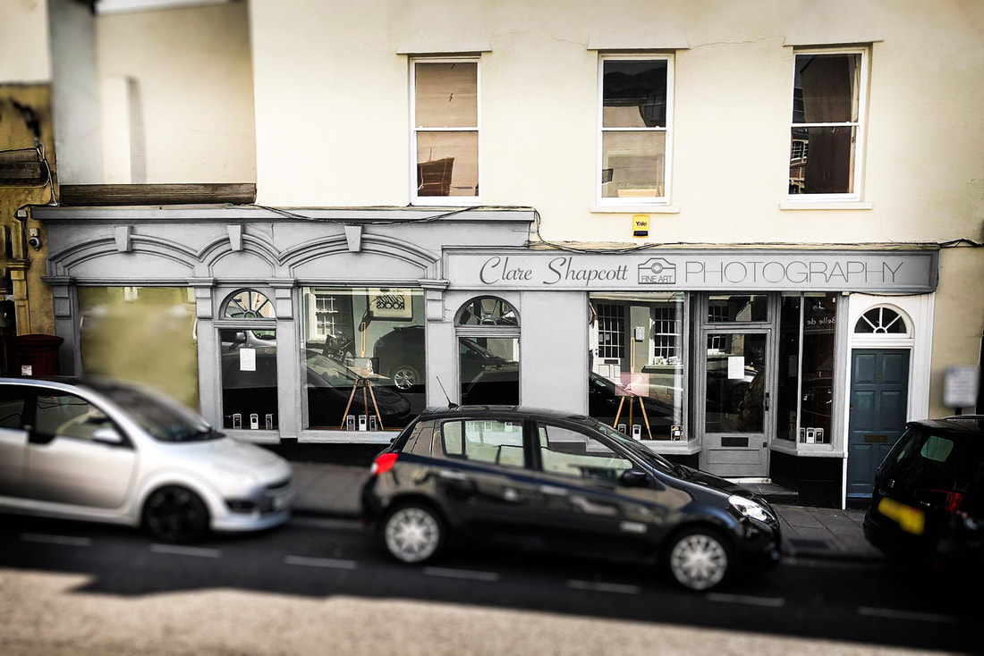 Outdoor photograph of studio shop front on a hill with some cars in front