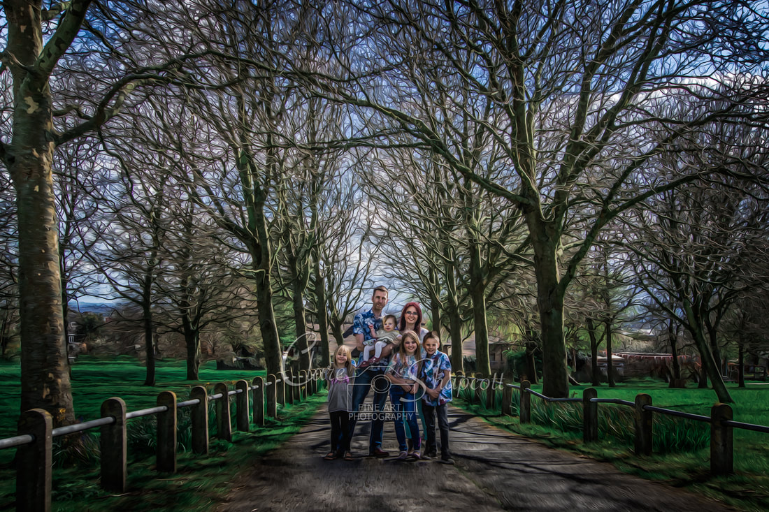 Family with children stand together outside on path surrounded by leaf-less trees.