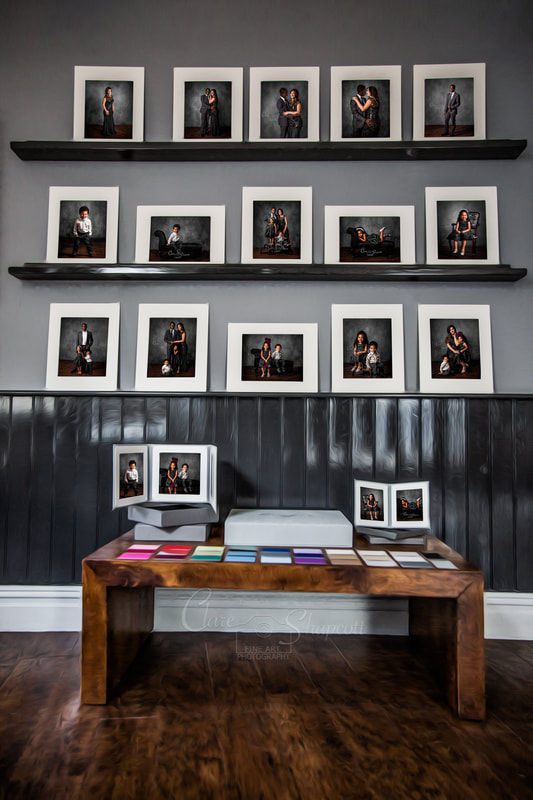 Display wall showing gallery of family photographs above a table with folio displays and various colour swatches.
