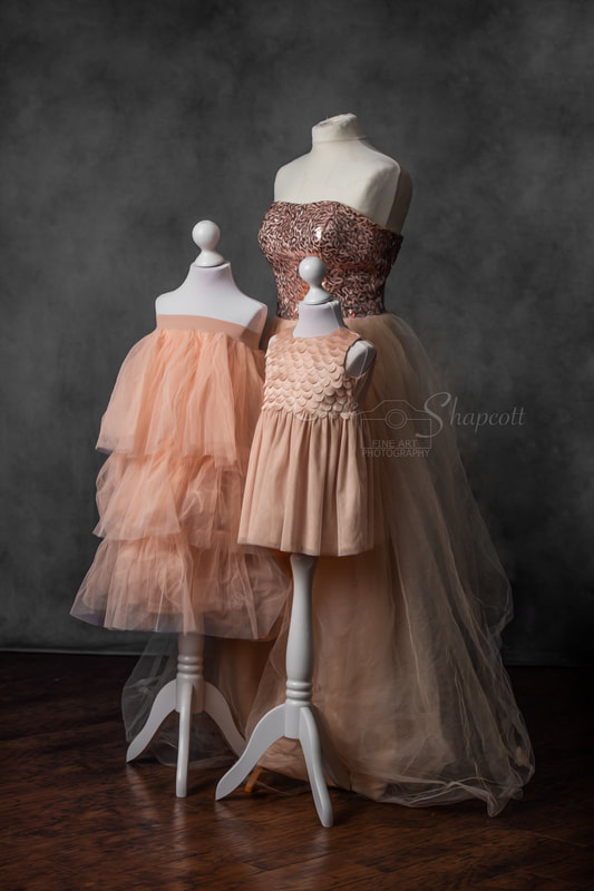 Three cream and orange coloured dresses on mannequins, each with a different elegant style and of different sizes.