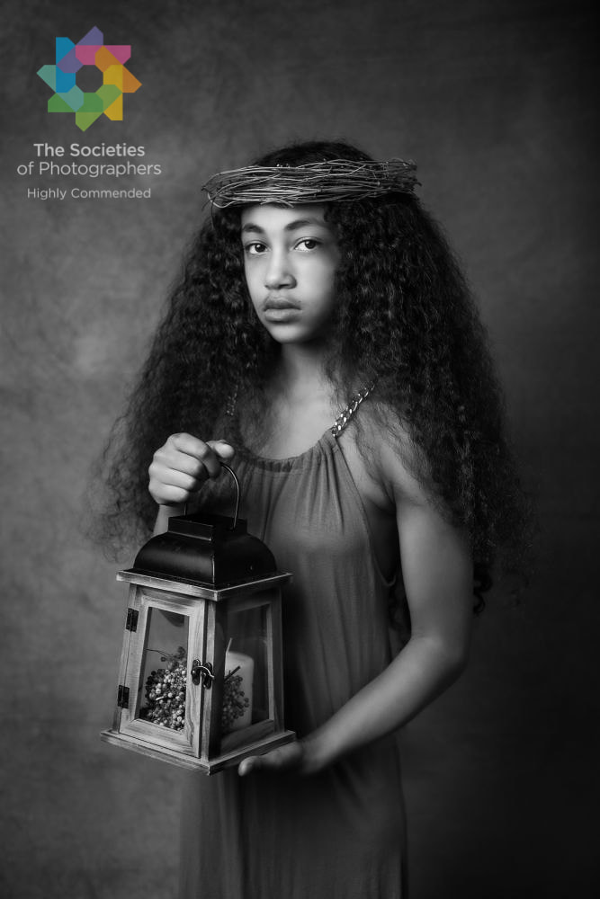 Black and white photograph of teenage girl with long curly hair holding lantern.