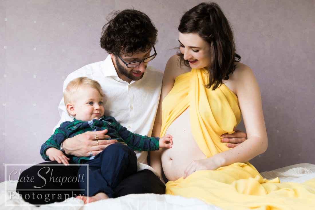 Baby boy touching mother's baby bump in photograph with father
